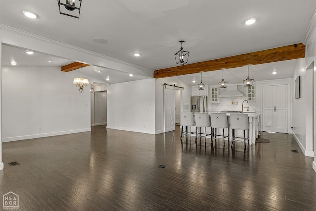 unfurnished living room featuring recessed lighting, a barn door, and baseboards