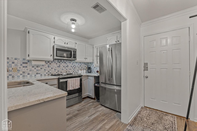 1300 S Church St S, Jonesboro, AR 72401 - kitchen featuring stainless steel appliances, light stone counters, white cabinets, backsplash, and ornamental molding