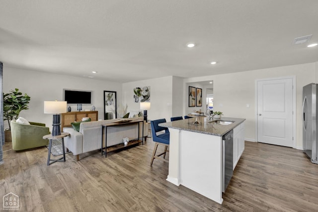 107 Terry Dr, Brookland, AR 72417 - kitchen featuring an island with sink, stainless steel appliances, stone countertops, a sink, and wood finished floors