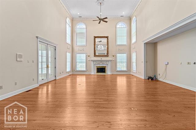3201 S 2nd Ave S, Paragould, AR 72450 - unfurnished living room with light wood-style flooring, a ceiling fan, a premium fireplace, a high ceiling, and crown molding