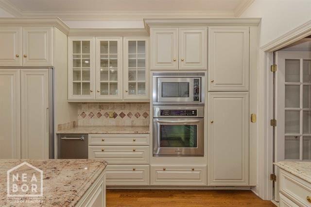 3201 S 2nd Ave S, Paragould, AR 72450 - kitchen with built in appliances, crown molding, glass insert cabinets, light stone counters, and wood finished floors