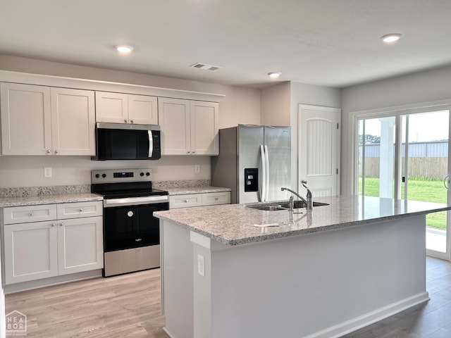 119 Terry Dr, Brookland, AR 72417 - kitchen with appliances with stainless steel finishes, light wood-type flooring, recessed lighting, a center island with sink, and white cabinetry