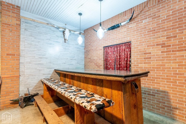 bar with a bar, brick wall, and pendant lighting