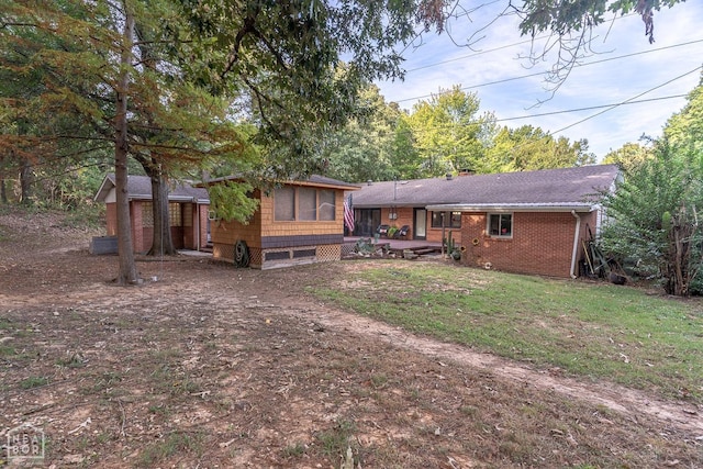 rear view of house featuring brick siding and a lawn