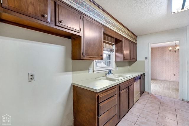kitchen with dishwashing machine, a textured ceiling, a chandelier, light countertops, and a sink