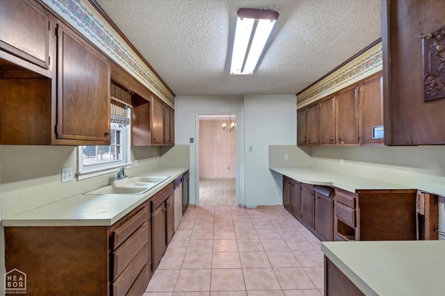 kitchen featuring light tile patterned floors, light countertops, a textured ceiling, dishwasher, and a sink