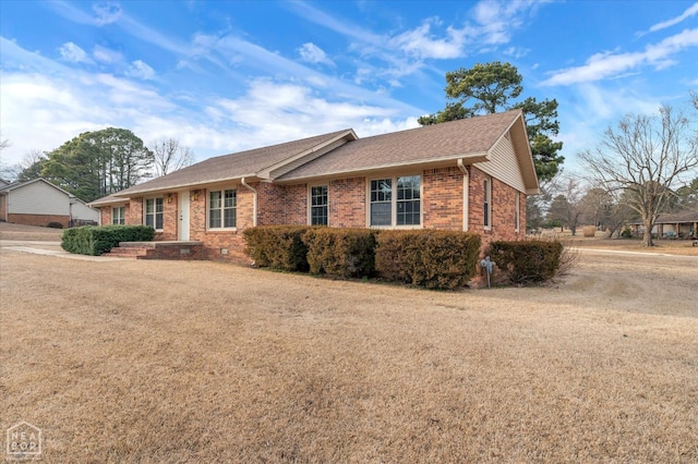 ranch-style house featuring brick siding, a front lawn, and a shingled roof