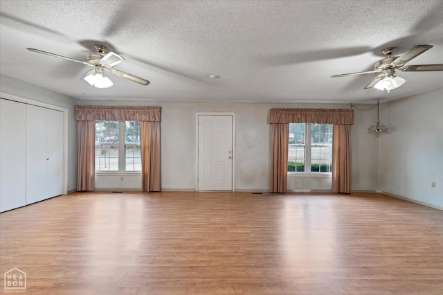unfurnished living room featuring a ceiling fan, plenty of natural light, and light wood-style floors