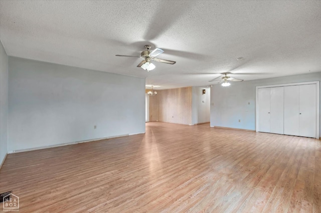 unfurnished living room with light wood finished floors, ceiling fan with notable chandelier, and a textured ceiling