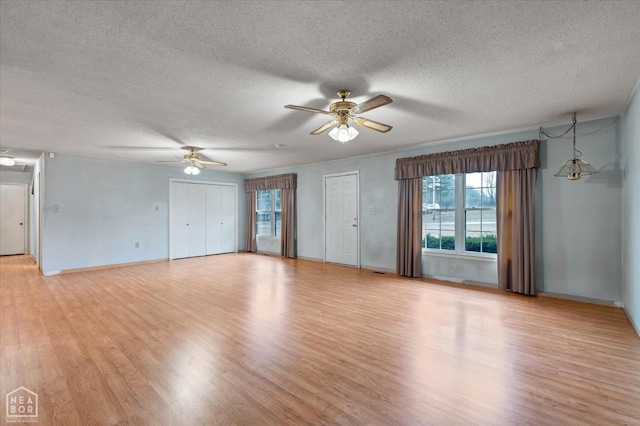 unfurnished living room featuring baseboards, light wood-style flooring, a textured ceiling, and a ceiling fan
