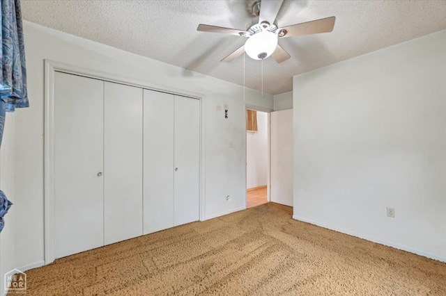 unfurnished bedroom featuring a closet, a ceiling fan, carpet floors, and a textured ceiling
