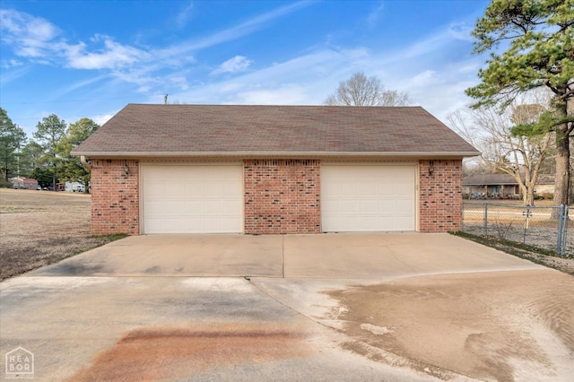 garage featuring concrete driveway and fence