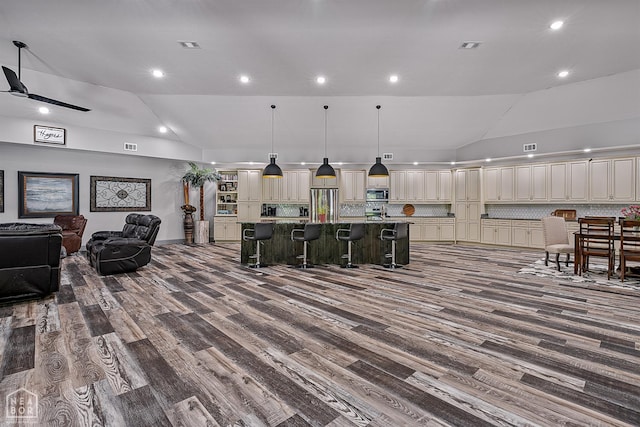8203 Oak Creek Ln, Harrisburg, AR 72432 - kitchen featuring appliances with stainless steel finishes, lofted ceiling, a kitchen bar, open floor plan, and dark wood-style flooring