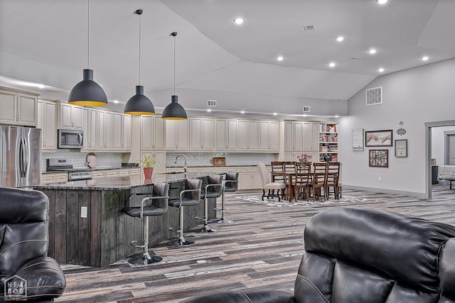 8203 Oak Creek Ln, Harrisburg, AR 72432 - kitchen with appliances with stainless steel finishes, decorative backsplash, a breakfast bar, dark stone counters, and wood finished floors