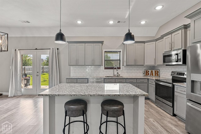 506 S Edmonds St, Monette, AR 72447 - kitchen with gray cabinetry, appliances with stainless steel finishes, a sink, light wood-type flooring, and a kitchen bar