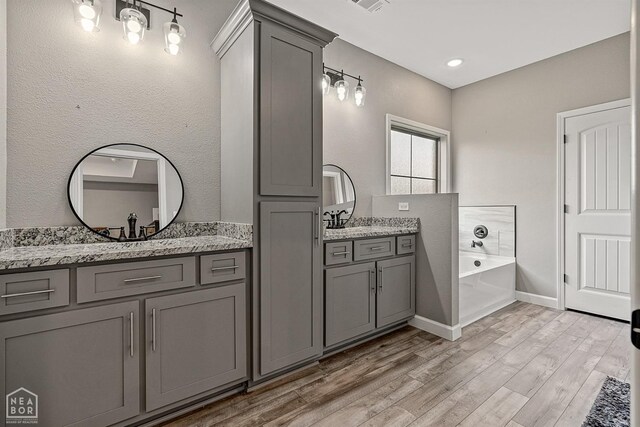 506 S Edmonds St, Monette, AR 72447 - full bathroom featuring vanity, a garden tub, and wood finished floors