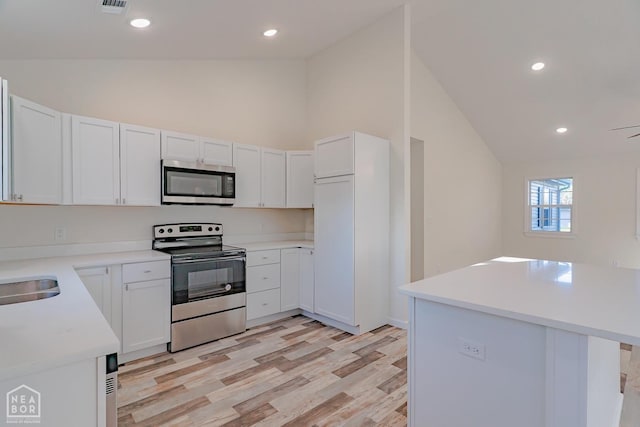 2516 Rebecca Dr, Pocahontas, AR 72455 - kitchen with stainless steel appliances, light wood finished floors, light countertops, white cabinets, and high vaulted ceiling