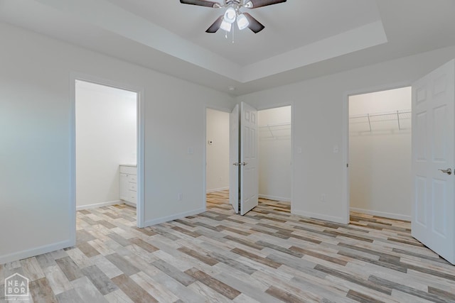 2516 Rebecca Dr, Pocahontas, AR 72455 - unfurnished bedroom featuring light wood-style floors, multiple closets, ensuite bathroom, a tray ceiling, and a ceiling fan