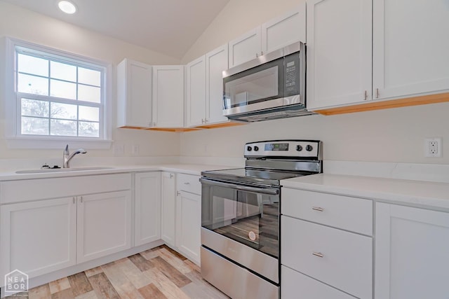2516 Rebecca Dr, Pocahontas, AR 72455 - kitchen featuring appliances with stainless steel finishes, white cabinets, light countertops, lofted ceiling, and light wood-type flooring