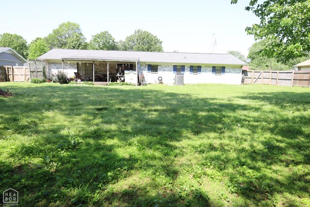 rear view of property featuring a lawn, a fenced backyard, and central air condition unit