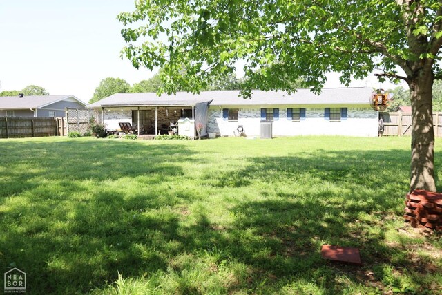 rear view of property featuring a lawn, a fenced backyard, and central air condition unit