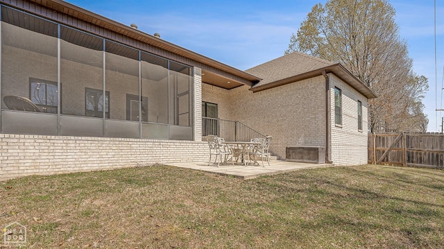 back of property featuring a patio, a sunroom, fence, a lawn, and brick siding