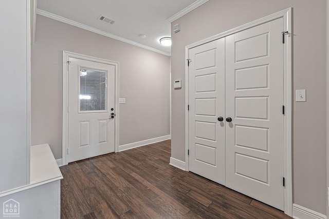 foyer entrance featuring crown molding, dark wood finished floors, visible vents, and baseboards