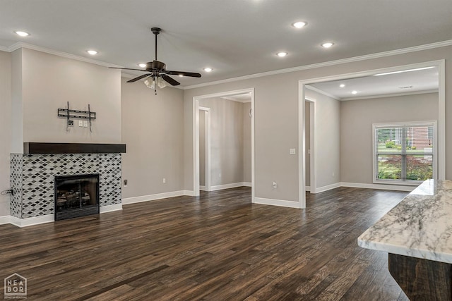 unfurnished living room featuring baseboards, ornamental molding, dark wood finished floors, a tiled fireplace, and ceiling fan
