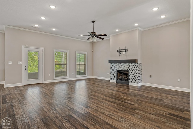 unfurnished living room featuring a ceiling fan, recessed lighting, crown molding, a tile fireplace, and dark wood-style floors