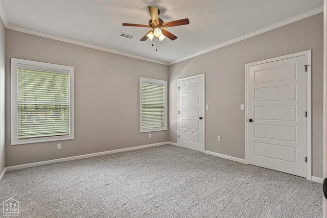 empty room featuring ceiling fan, ornamental molding, visible vents, and carpet floors