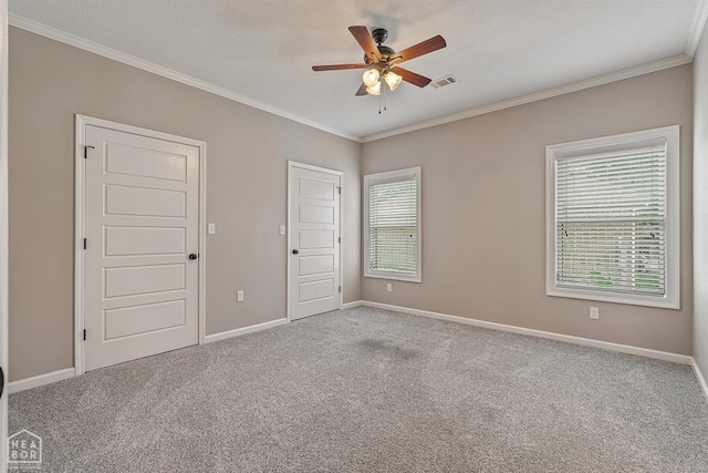 spare room featuring a ceiling fan, baseboards, carpet flooring, visible vents, and crown molding