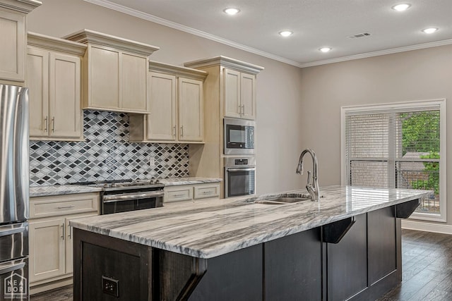 kitchen with light stone countertops, visible vents, a sink, stainless steel appliances, and a kitchen island with sink