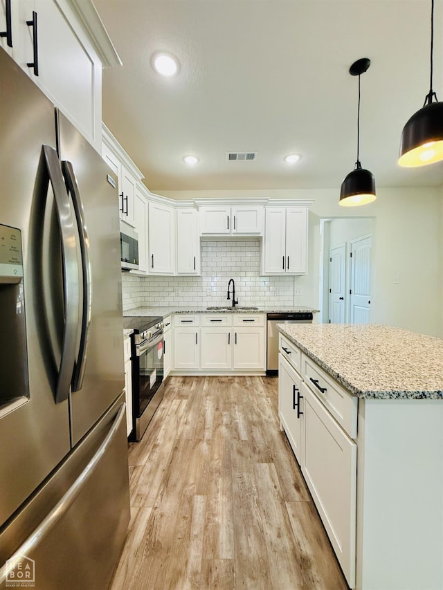 kitchen with light wood-style floors, decorative backsplash, white cabinetry, and stainless steel appliances