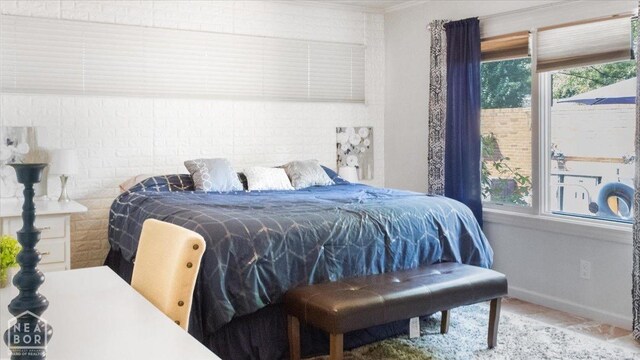 bedroom with brick wall, multiple windows, and baseboards