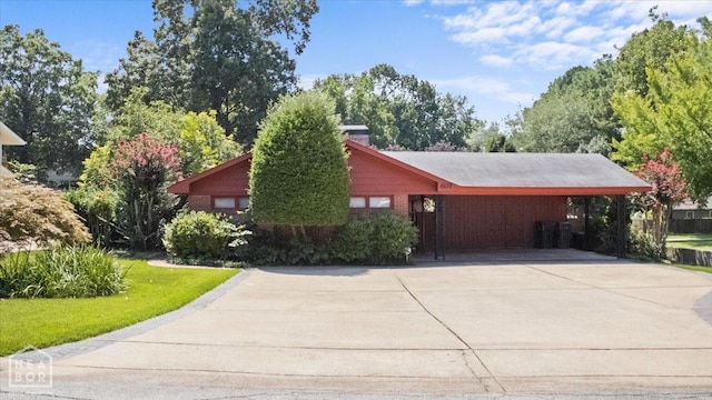 view of side of property featuring a carport, a yard, and concrete driveway