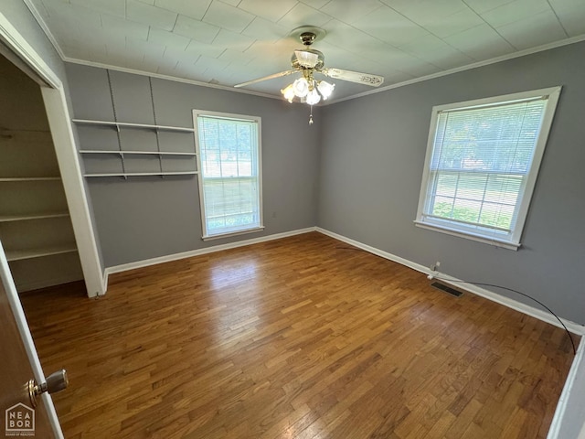 937 Homecrest Dr, Piggott, AR 72454 - unfurnished bedroom featuring crown molding, multiple windows, wood finished floors, and a ceiling fan
