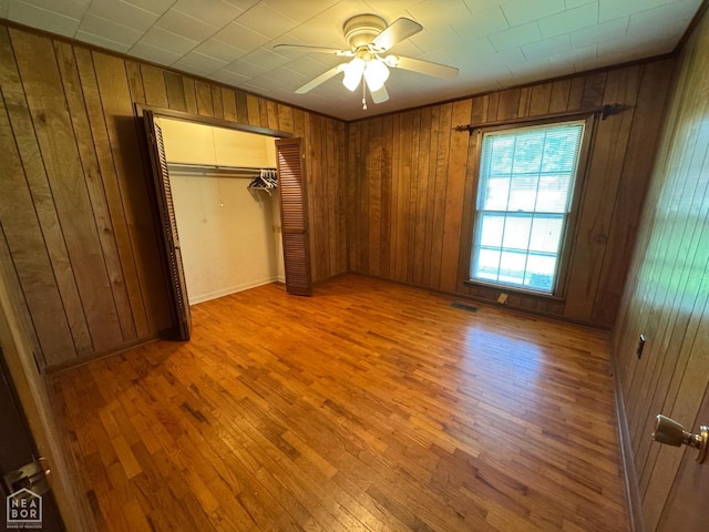 937 Homecrest Dr, Piggott, AR 72454 - unfurnished bedroom with wooden walls, wood finished floors, a closet, and a ceiling fan
