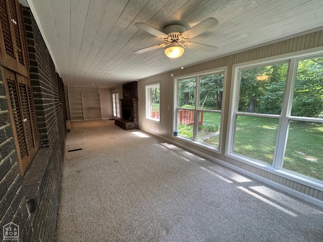 937 Homecrest Dr, Piggott, AR 72454 - unfurnished living room featuring wood ceiling, wood walls, carpet floors, a ceiling fan, and a fireplace