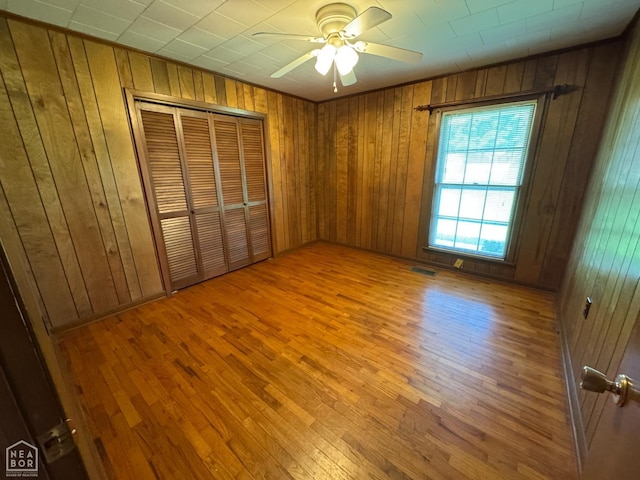 937 Homecrest Dr, Piggott, AR 72454 - unfurnished bedroom with wood walls, wood finished floors, a closet, and ceiling fan