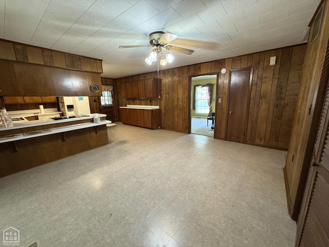 937 Homecrest Dr, Piggott, AR 72454 - kitchen with wooden walls, light floors, a ceiling fan, light countertops, and brown cabinetry