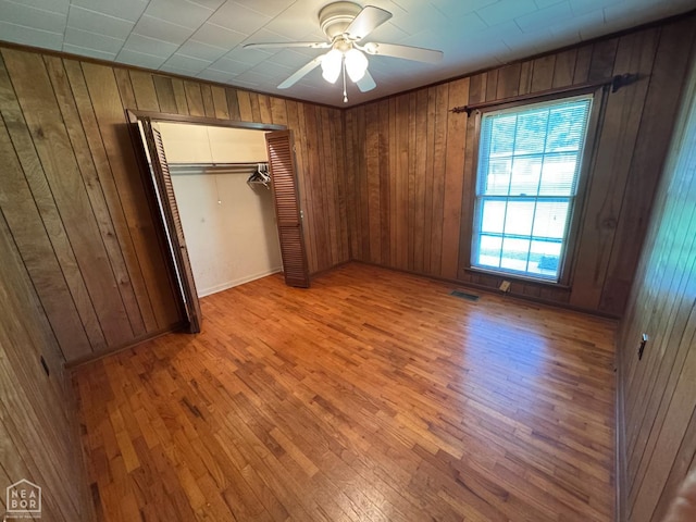 937 Homecrest Dr, Piggott, AR 72454 - unfurnished bedroom with wood walls, light wood-style flooring, a closet, and ceiling fan