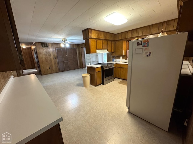 937 Homecrest Dr, Piggott, AR 72454 - kitchen with electric range, freestanding refrigerator, wooden walls, brown cabinetry, and light countertops
