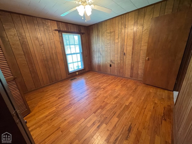 937 Homecrest Dr, Piggott, AR 72454 - unfurnished bedroom featuring wood finished floors, wooden walls, and a ceiling fan