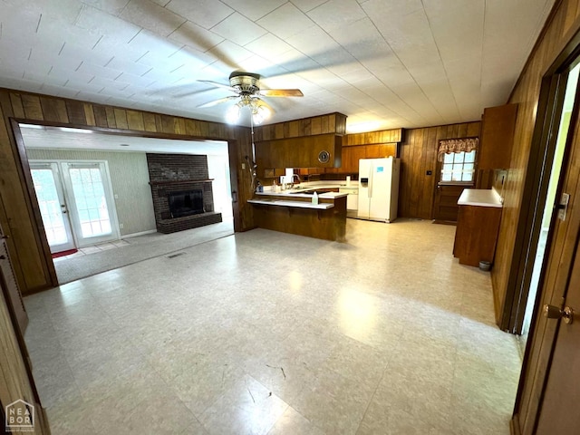 937 Homecrest Dr, Piggott, AR 72454 - kitchen featuring white refrigerator with ice dispenser, wooden walls, a peninsula, open floor plan, and brown cabinetry
