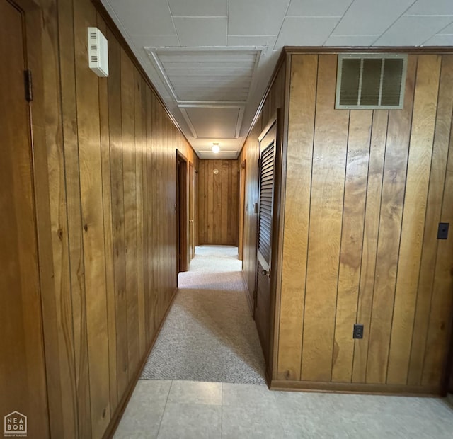 937 Homecrest Dr, Piggott, AR 72454 - corridor featuring attic access, wood walls, light colored carpet, and light tile patterned floors