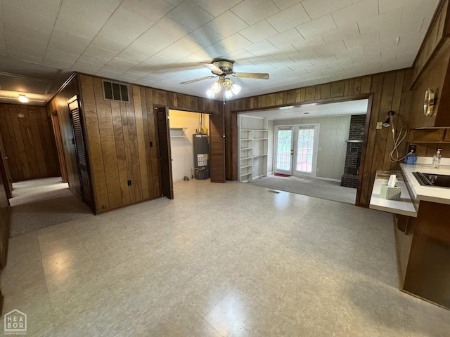 937 Homecrest Dr, Piggott, AR 72454 - unfurnished living room with wooden walls, gas water heater, a ceiling fan, light floors, and french doors