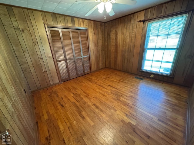 937 Homecrest Dr, Piggott, AR 72454 - unfurnished bedroom with wooden walls, hardwood / wood-style flooring, a closet, and a ceiling fan
