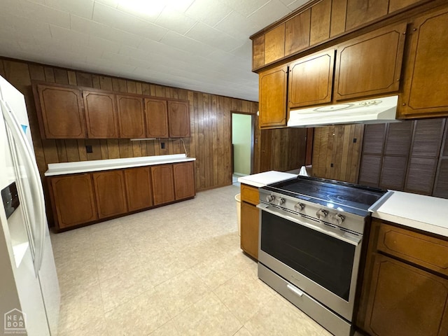 937 Homecrest Dr, Piggott, AR 72454 - kitchen featuring stainless steel range with electric cooktop, under cabinet range hood, brown cabinets, wooden walls, and light countertops