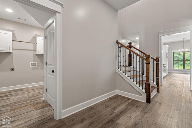 stairs featuring visible vents, baseboards, an inviting chandelier, and wood finished floors