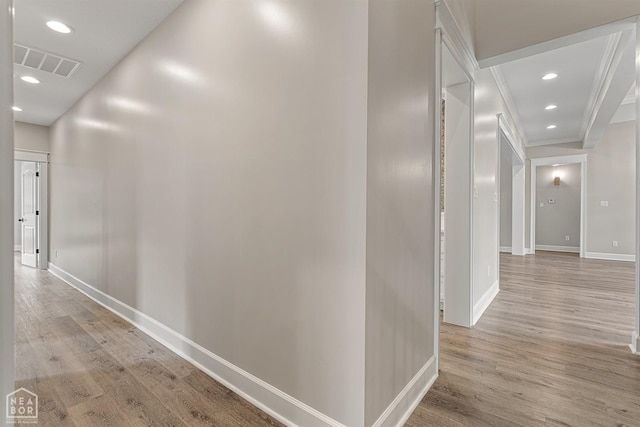 corridor featuring visible vents, baseboards, ornamental molding, light wood-type flooring, and recessed lighting